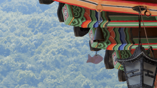 산을 배경으로 한 전통 한옥 처마 밑 생선 풍종