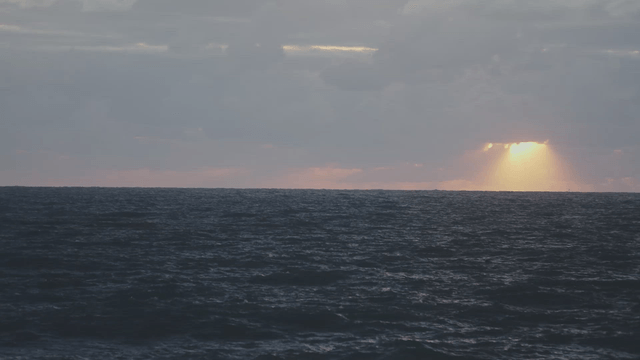 Sunlight falling through clouds over a wavering sea