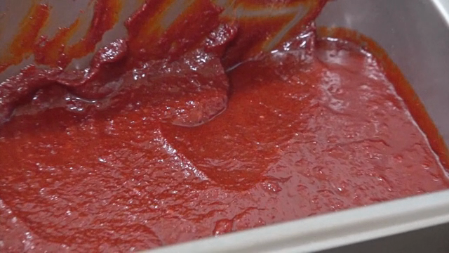 A container of red pepper paste on a stove