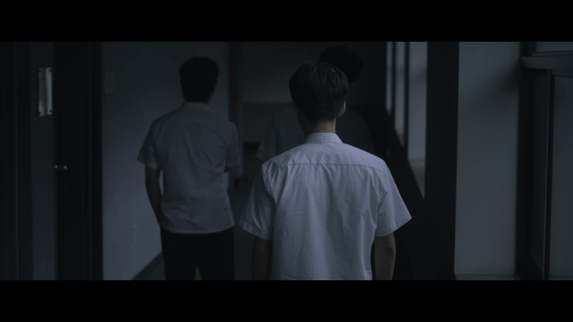 Male student turning back while walking in dark hallway