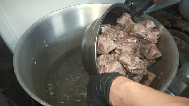 Boiled meat being poured into a large pot