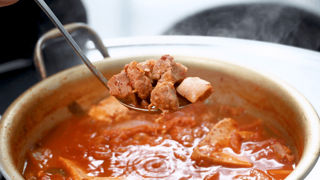 Pork in boiling kimchi stew scooped with ladle