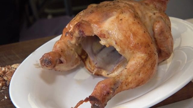 A roasted chicken being prepared on a plate