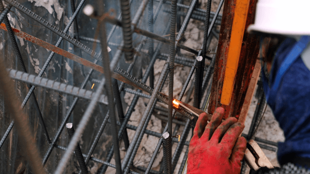 Worker welding steel bars at a construction site