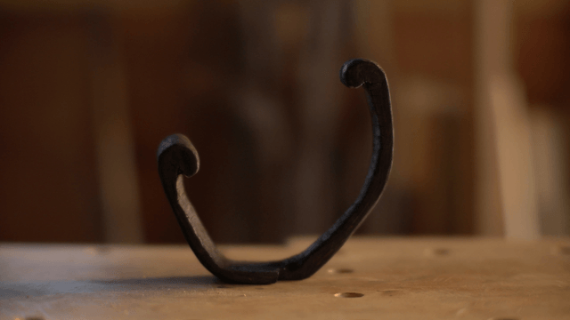 Dark wooden hook sculpture on wooden workbench