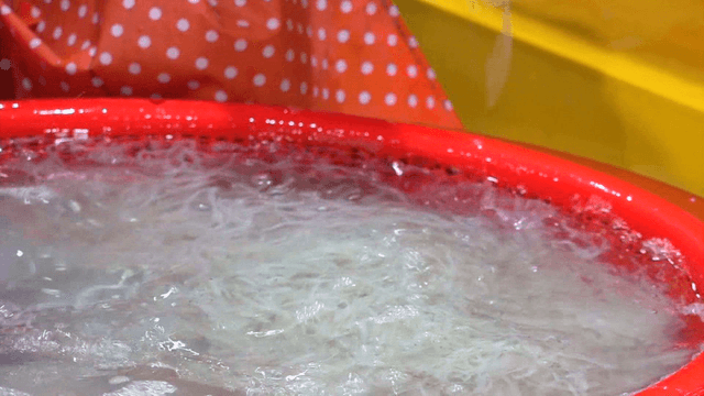 Vendor preparing ice fish with chopsticks in red basket