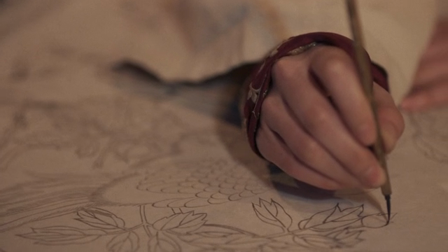 A hand painting an elaborate picture with a brush