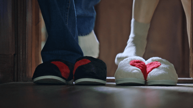 A couple wearing matching slippers indoors