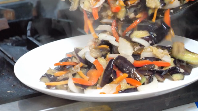 Stir-fried eggplant being served on a plate