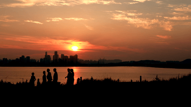 People walking by the river at sunset