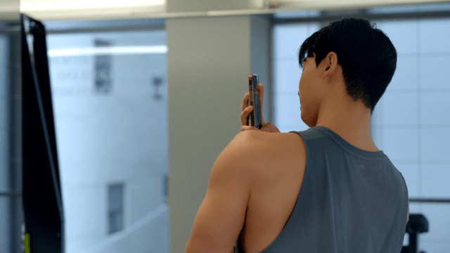 Young man taking a selfie in a gym mirror