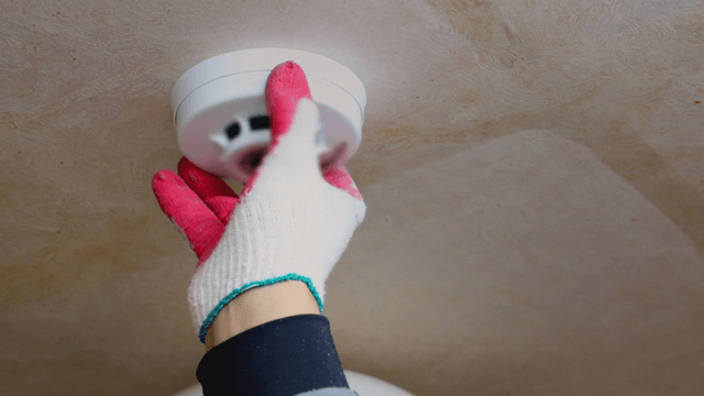 Person installing a smoke detector on the ceiling