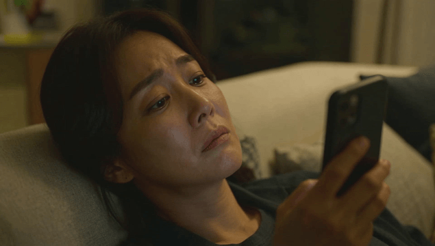 Woman using smartphone while lying on sofa