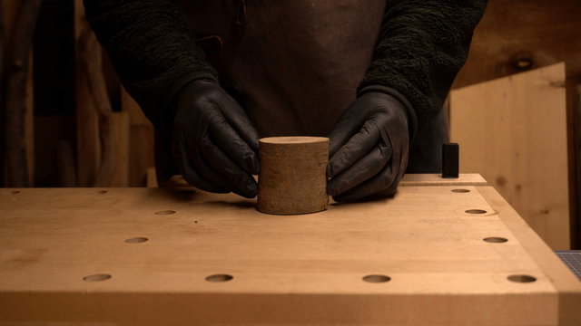 Gloved hands crafting a piece of wood