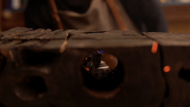 Woodcraft artisan burning holes in wooden piece with torch