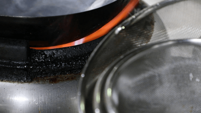 Wok on a stove with a flame