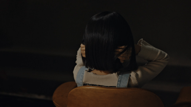 Child sitting on a chair indoors covering ears