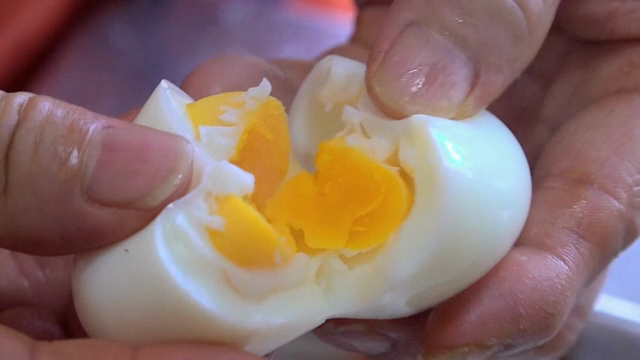 Hands cutting a boiled egg in half
