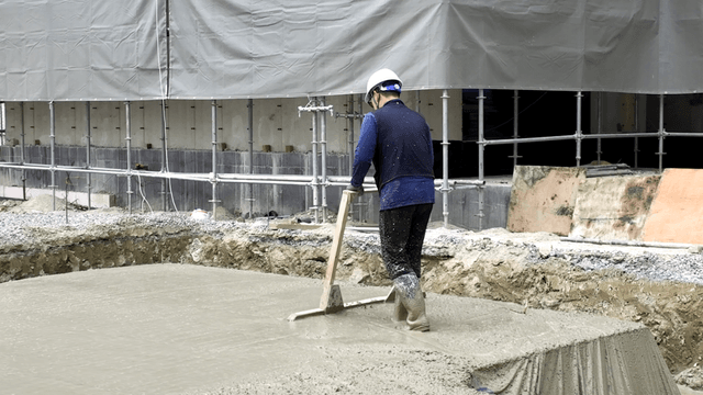 Worker smoothing concrete at a construction site