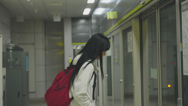 Young woman waiting in front of subway screen doors