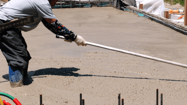 Worker leveling wet concrete at a site