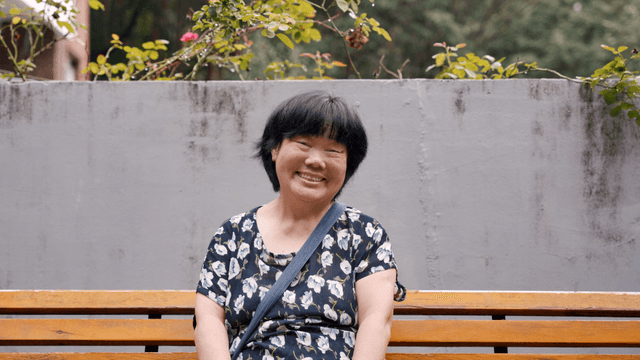 A smiling elderly woman sitting on a bench