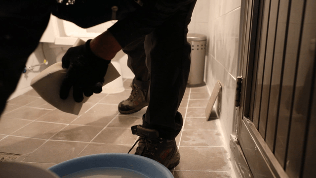 Worker plastering tiles in a bathroom