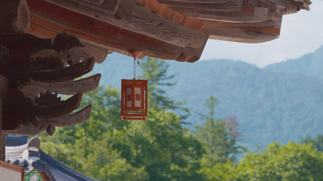 Lantern hanging from hanok eaves with distant mountain view
