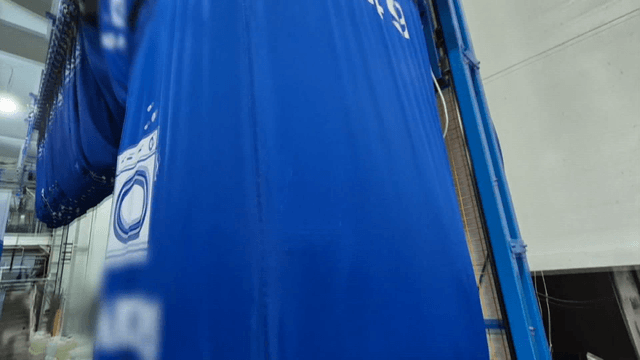 흰 천 더미들을 들어 올리는 세탁 공장 기계