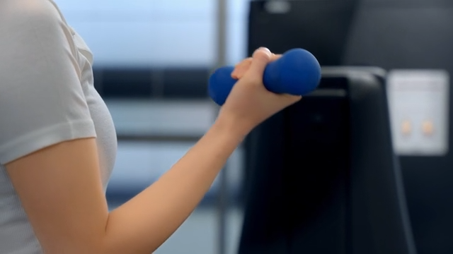 Exercising with small dumbbells in a gym woman