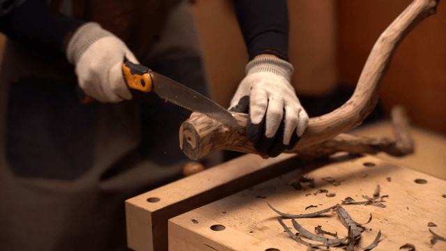 Person carefully sawing a wooden branch