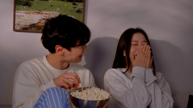Couple watching fun movie with popcorn on sofa