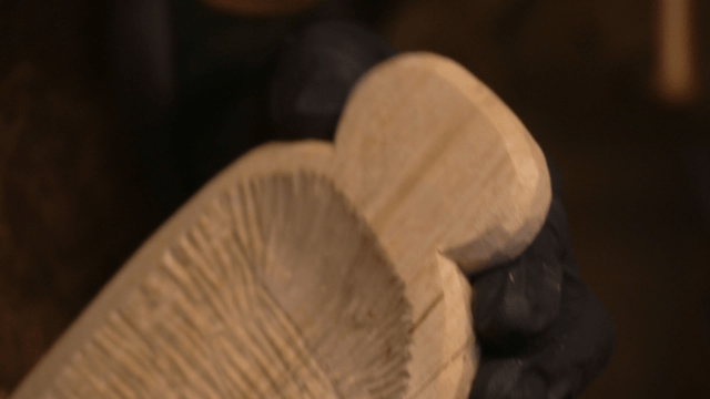 Hands carving wood piece with precise knife