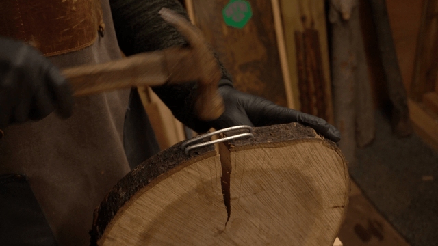 Craftsman hammering fixed wires into a log board