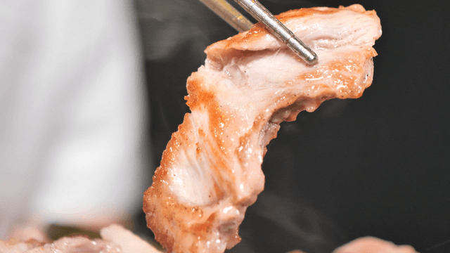 Grilled meat being picked up with chopsticks