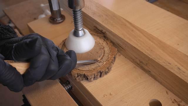 Craftsman carving wood with chisel and clamp