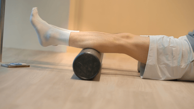 Man using foam roller for leg exercise