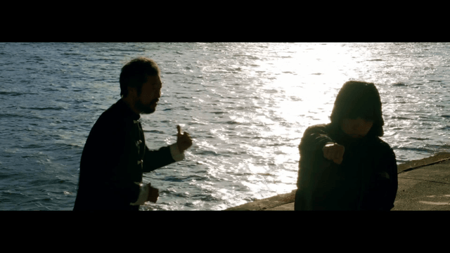 Two people practicing martial arts by the riverside