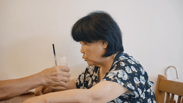 An elderly woman enjoying a drink indoors