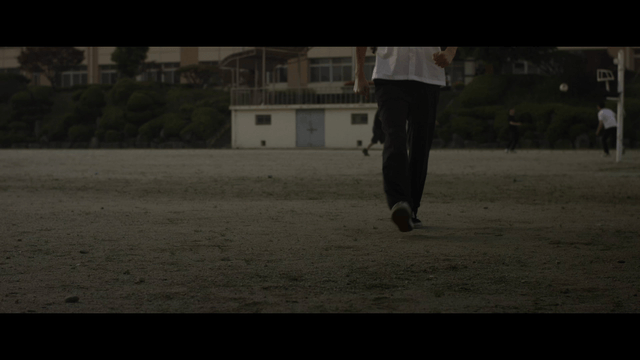 Student walking among students playing soccer on school field