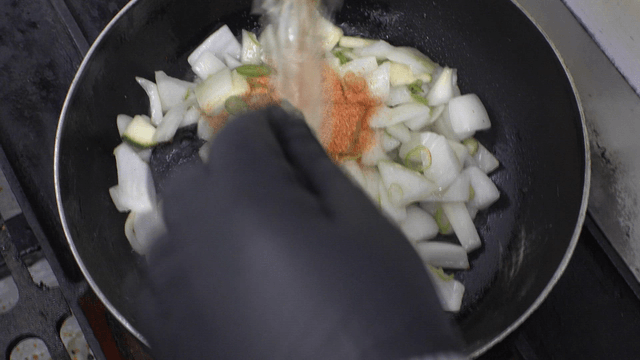 Special seasoning powder poured over vegetables being stir-fried in a pan