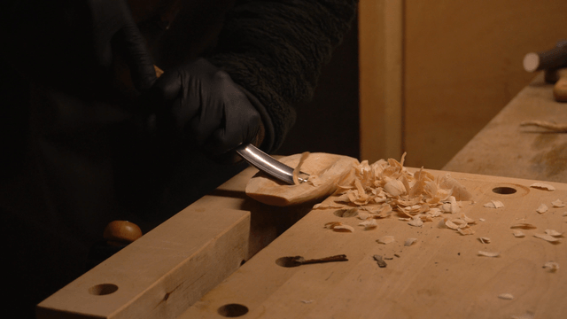 Woodcraft artisan carving grooves into wood with a chisel