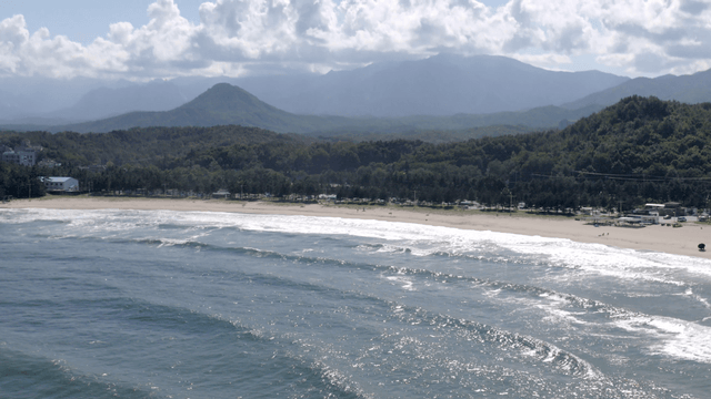 Quiet beach with waves and mountains