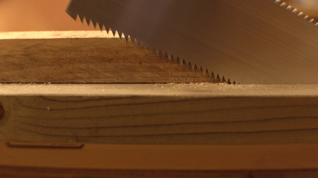 Saw cutting through a wooden plank