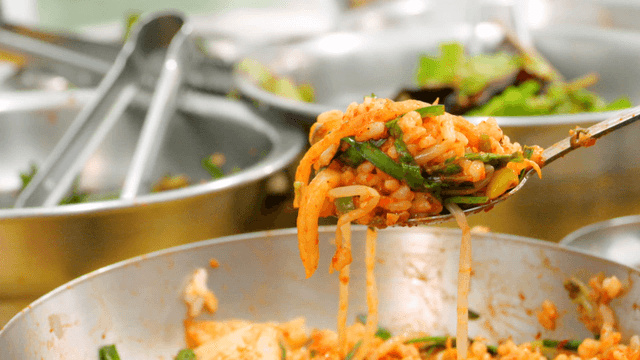 Spoon scooping bibimbap into stainless bowl