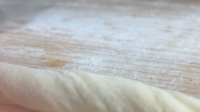 Hands shaping dough on a floured surface