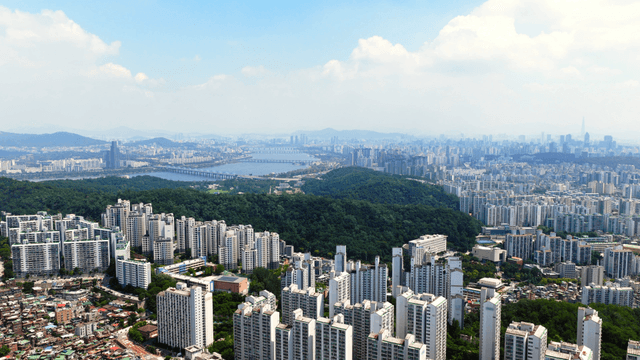 A vast cityscape with a river and greenery