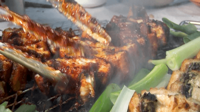 Eels grilled with green onions on metal grill