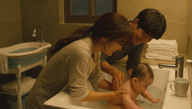 Parents bathing their baby in a bathroom sink