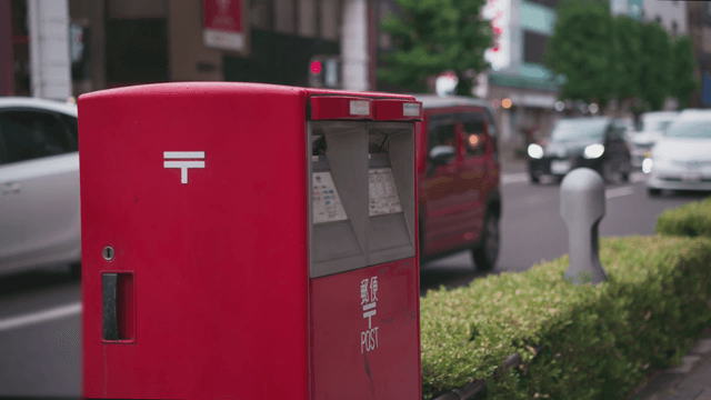 Red mailbox on busy Japanese city street